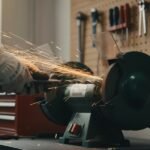 Sharpening a drill bit using a bench grinder in a workshop