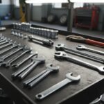 A complete collection of different wrench types and hand tools organized on a metal workshop cart in an automotive shop.
