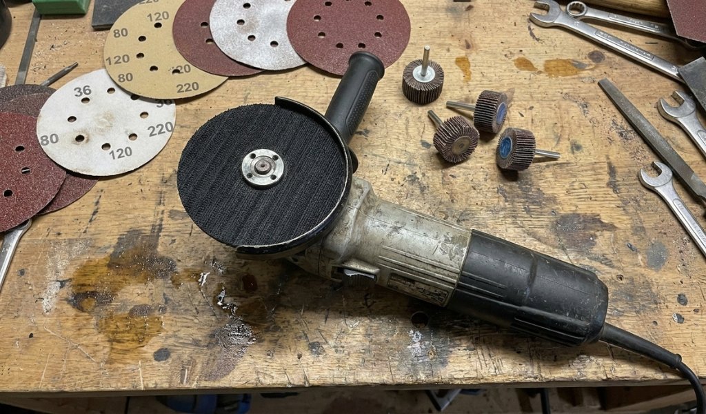 Hook and loop backing pad adapter mounted on an angle grinder for multi-grit wood sanding.