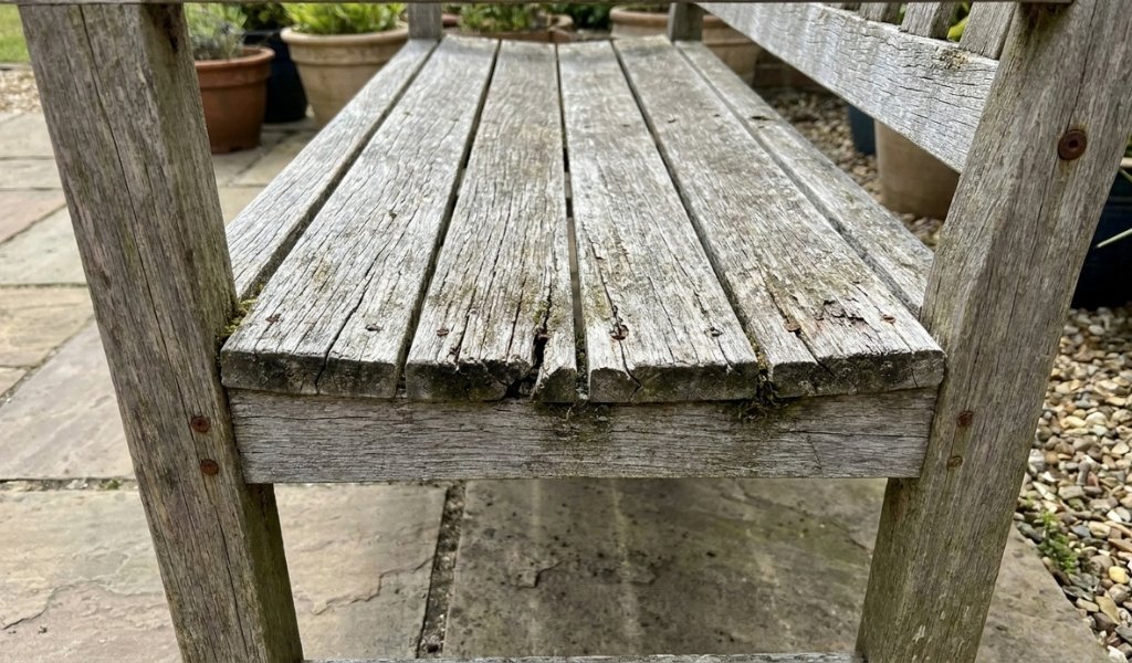 Outdoor acacia wood bench showing sun fading and graying from UV exposure